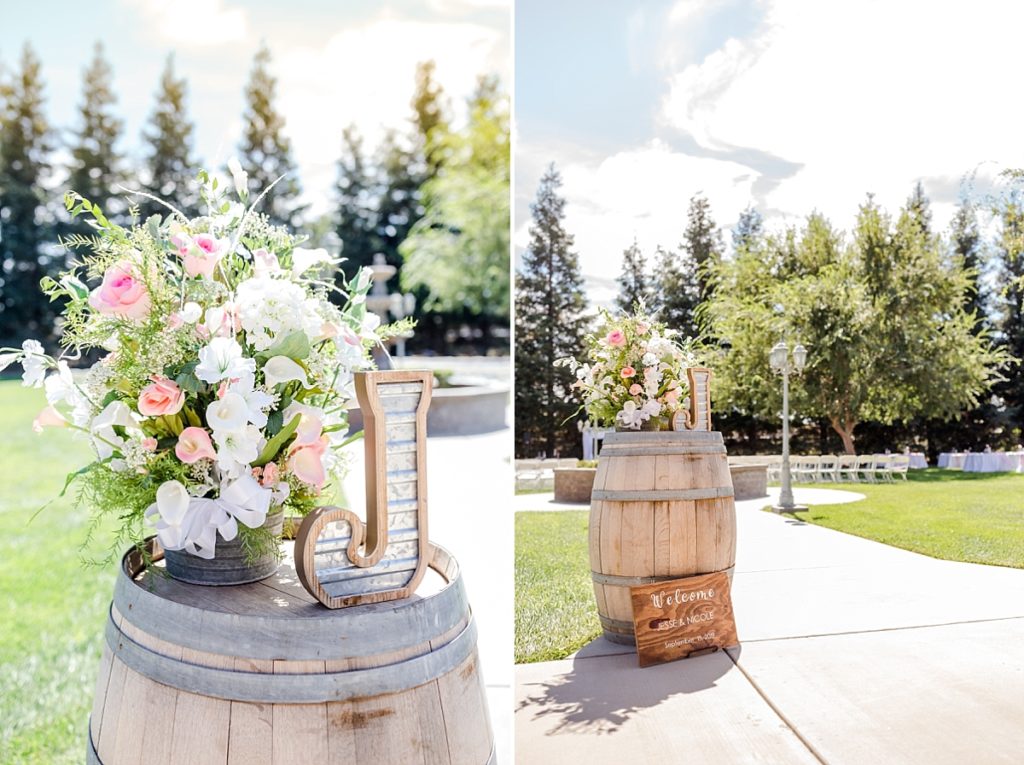 Rustic decorations at a wedding ceremony in the Central Valley of California. Wine barrel with letter and flower, trees in the background. Shot by Amber Rivas Photography.