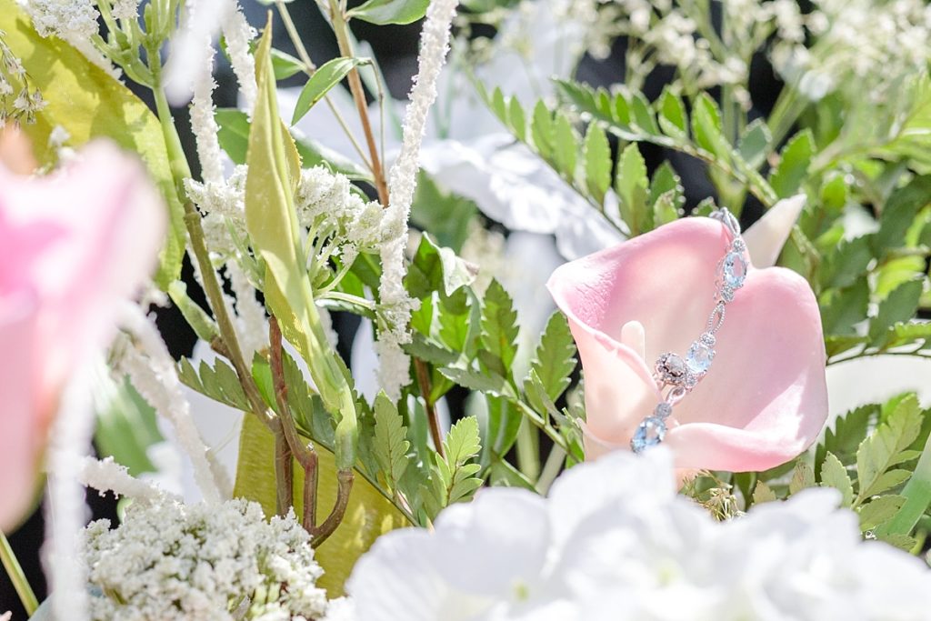 Bridal jewelry in a pink bouquet, diamond engagement ring and aquamarine bracelet. Shot by Amber Rivas Photography.