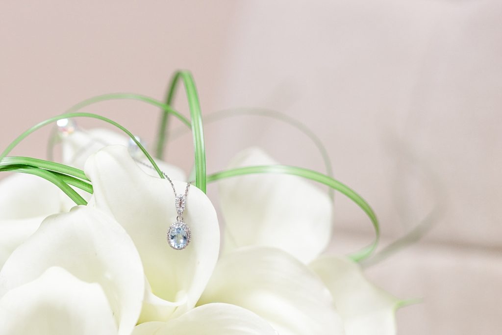 Aquamarine necklace on a white flower with a neutral background. Shot by Amber Rivas Photography.
