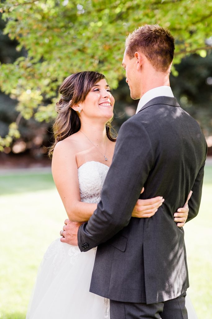 Bride and groom hugging and laughing in the church courtyard at Ceres Seventh-day Adventist Church. Shot by Amber Rivas Photography.