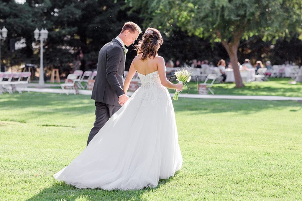 Bride and groom walking across the lawn towards the reception at Ceres Seventh-day Adventist Church. Shot by Amber Rivas Photography.