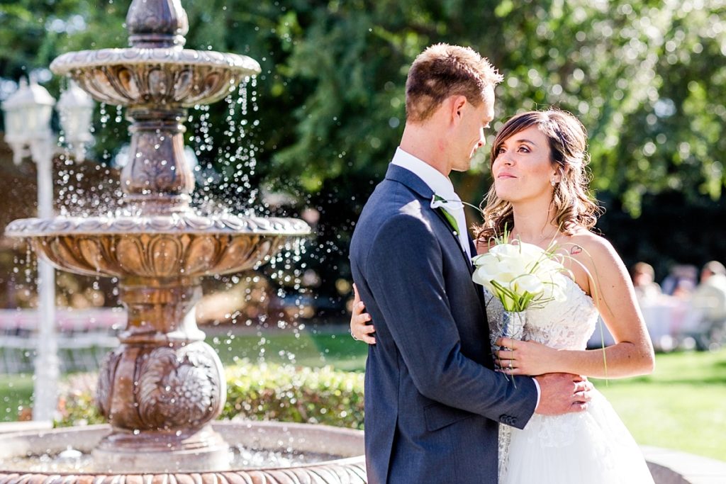 Bride and groom look into each others' eyes near the fountain at Ceres Seventh-day Adventist Church. Shot by Amber Rivas Photography.
