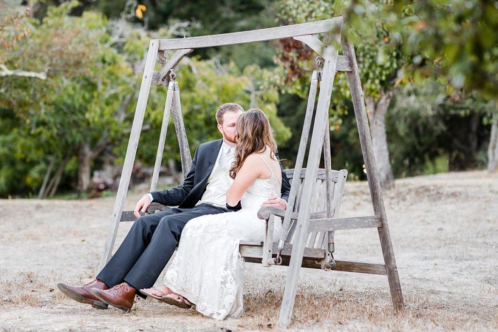 Bride and groom kiss on porch swing in Watsonville, CA at The Orchard.