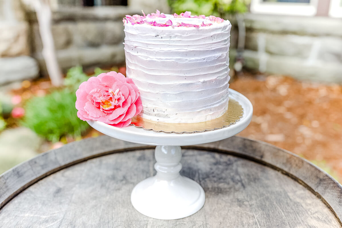 White bare cake on cake stand with pink flower