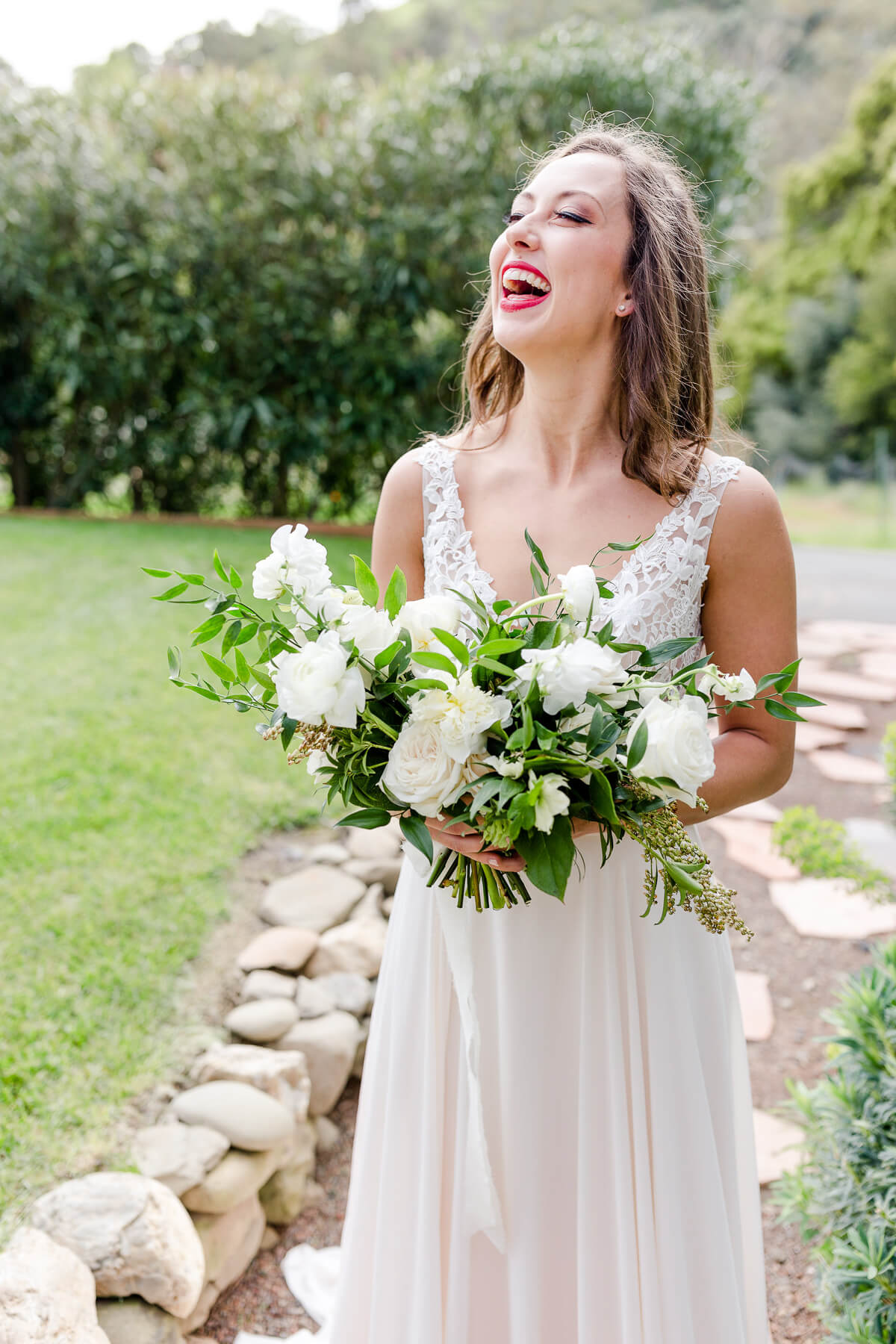 Bride at Elliston Vineyards laughs as she holds her bouquet