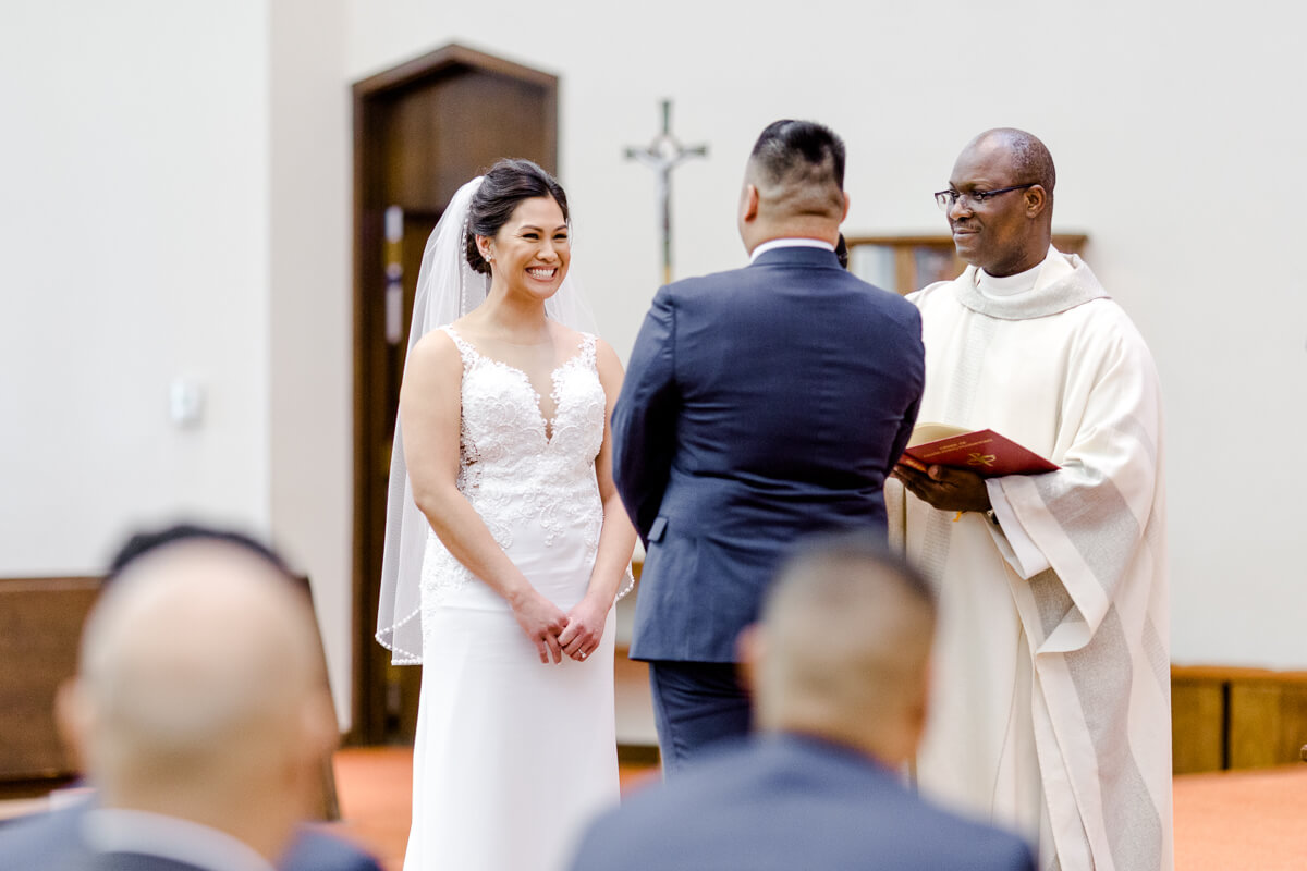 Catholic wedding ceremony, bride smiles at groom during homily