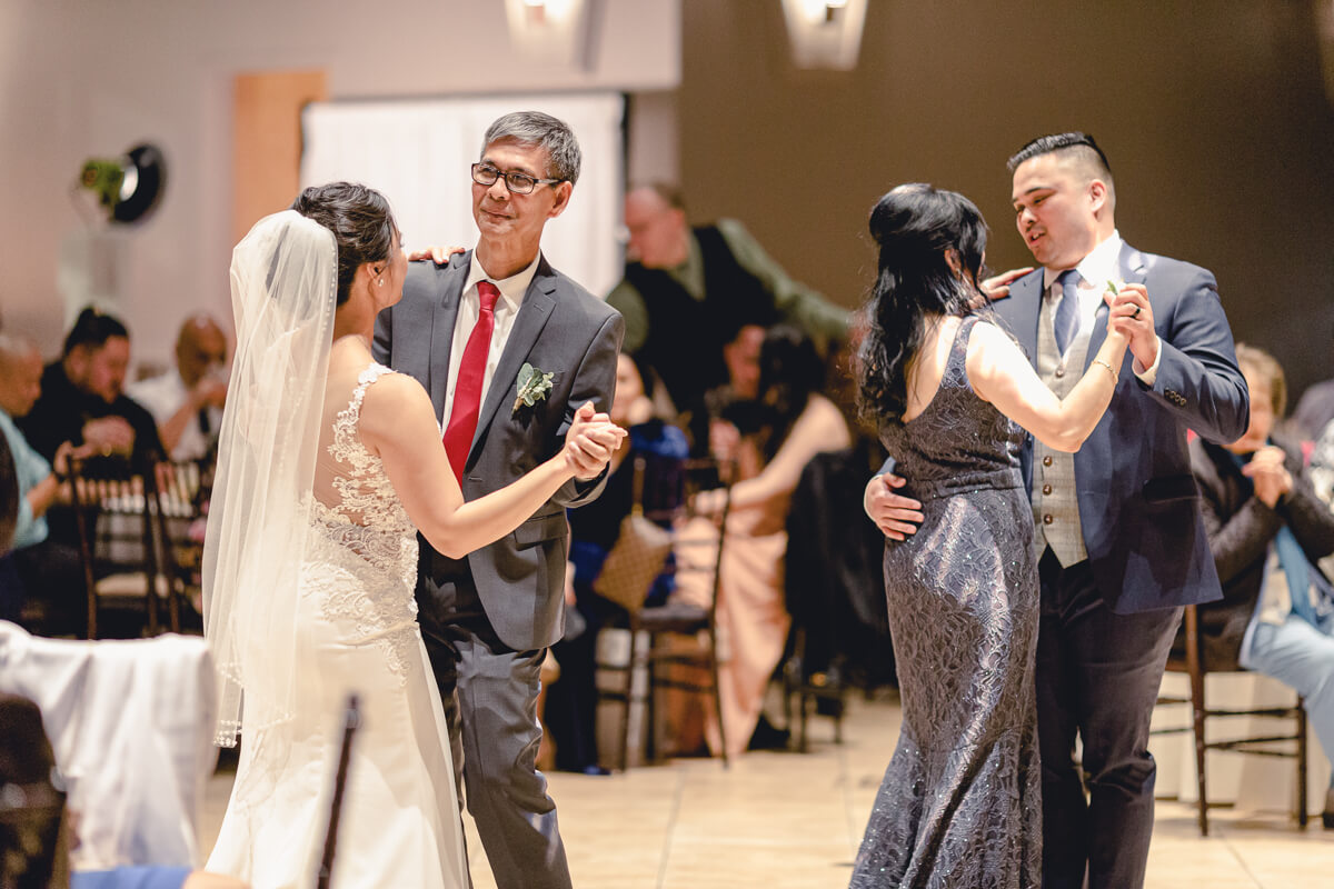 Bride and groom share a first dance with their parents during their Palm Event Center winter wedding