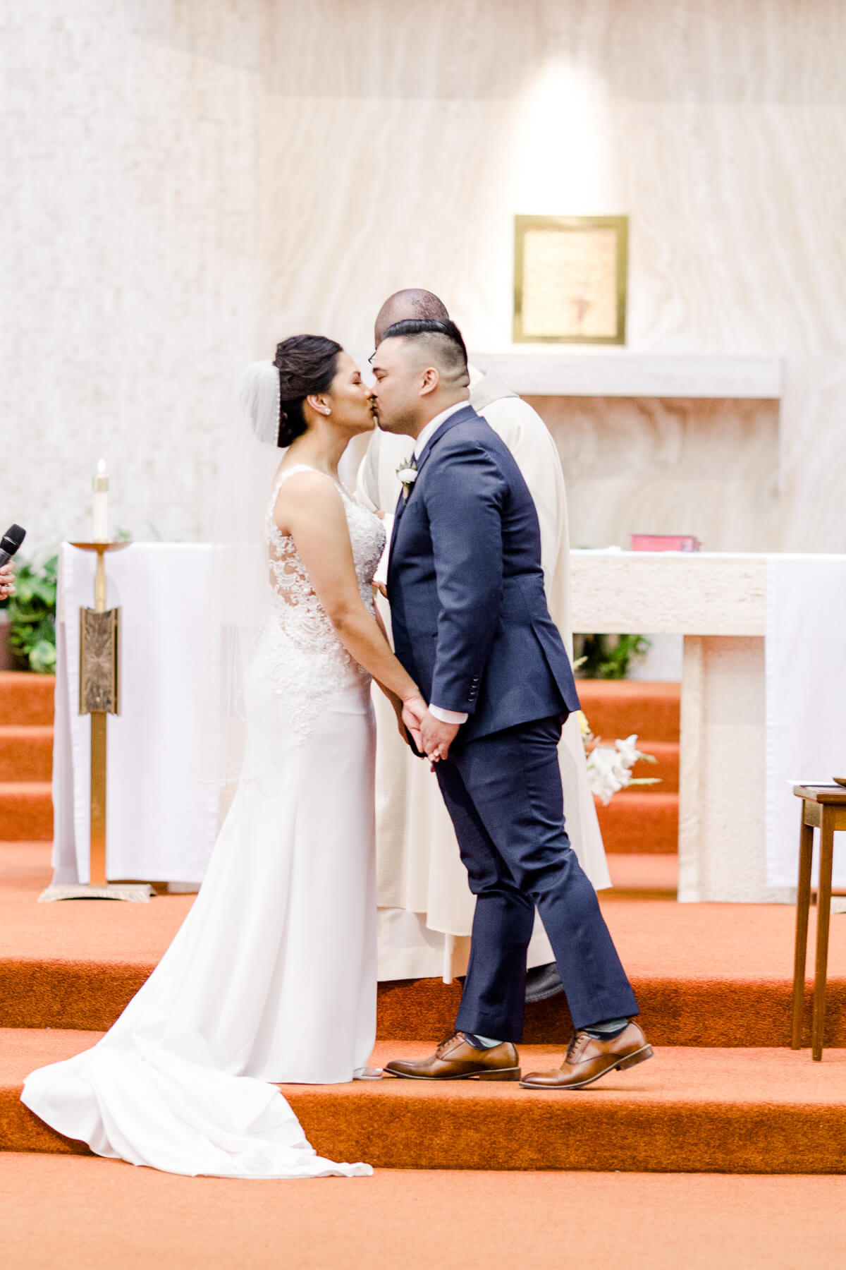 Bride and groom kiss at the altar at their Catholic winter wedding