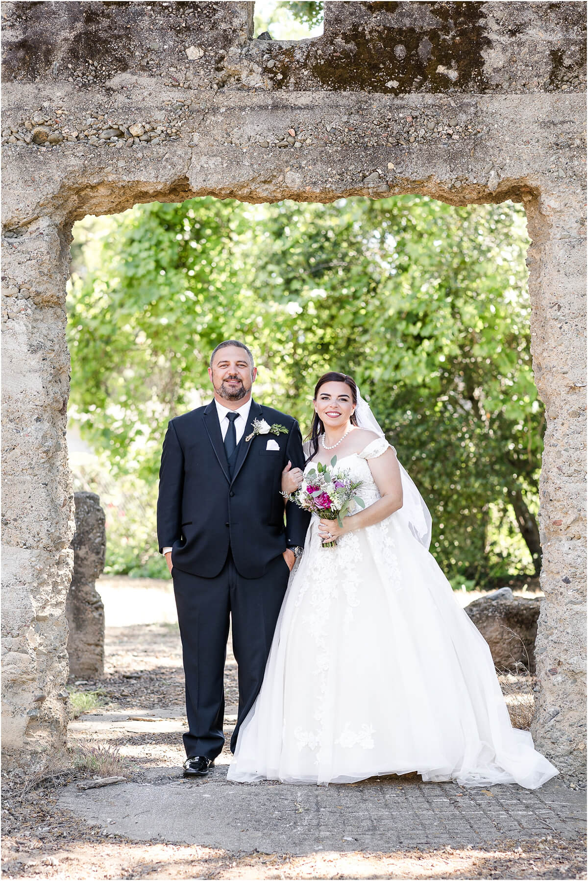 Bride and groom wedding portrait under the stone arch at Ravenswood Historic Site.