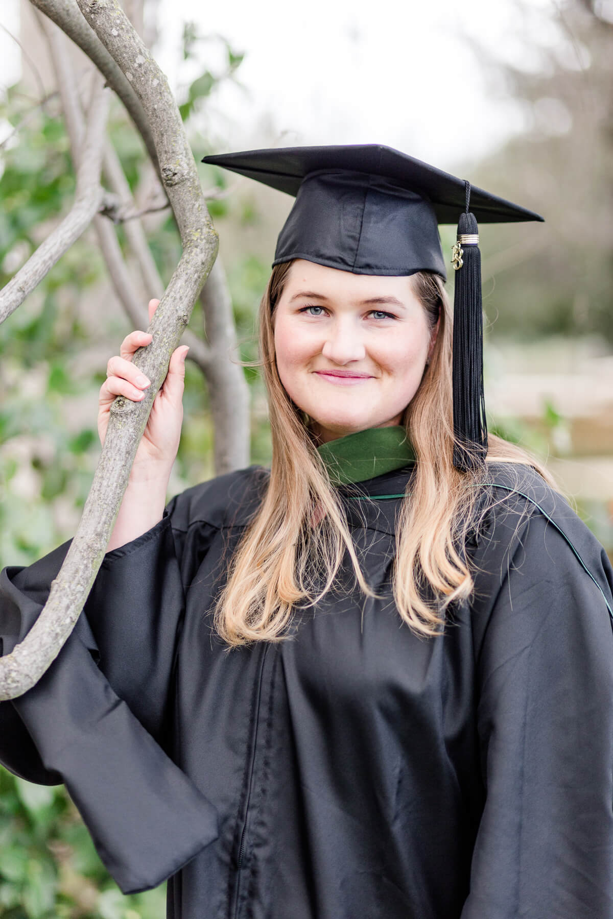 Woman in graduation gown holding onto vine