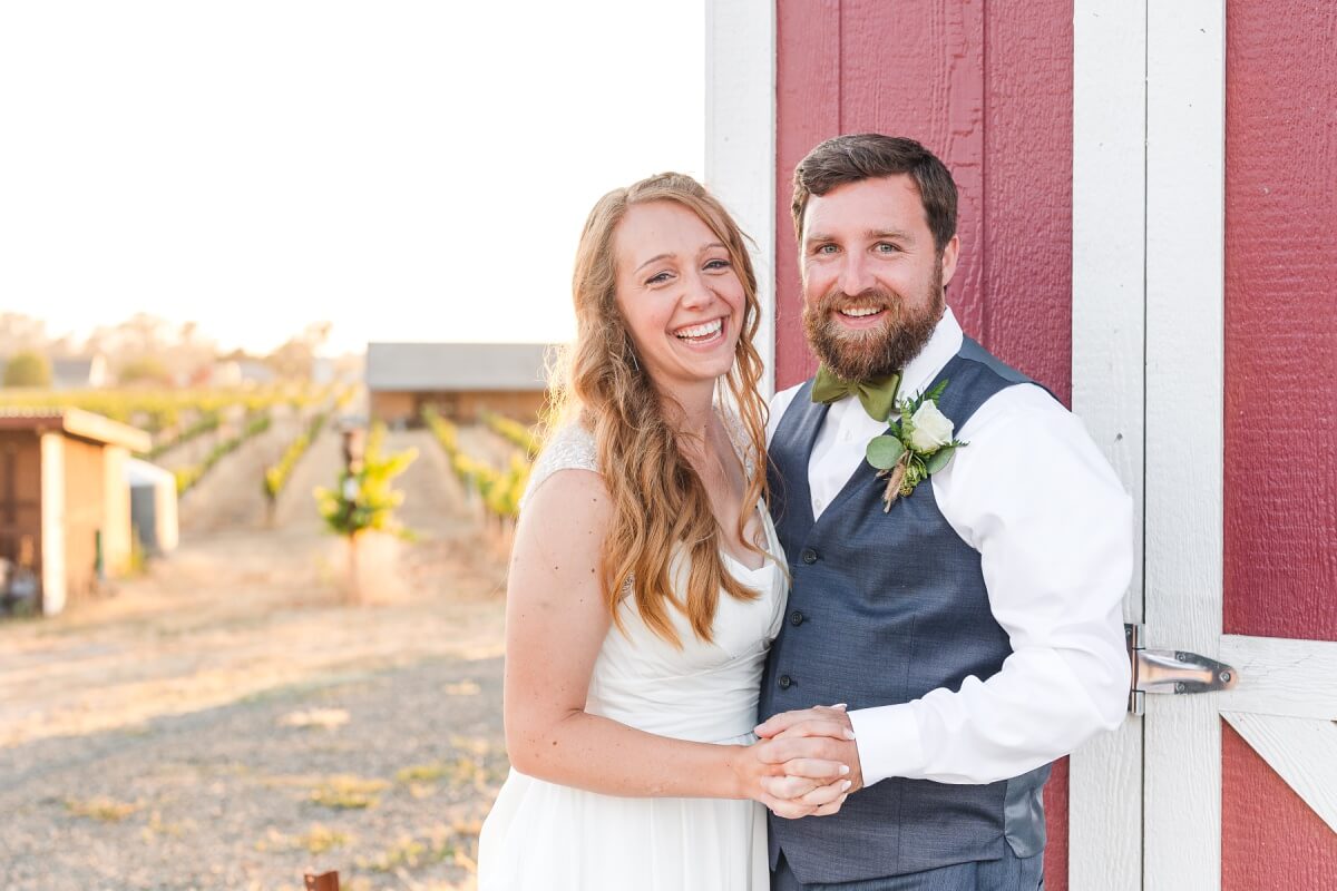 Bride and groom smiling near a barn at sunset